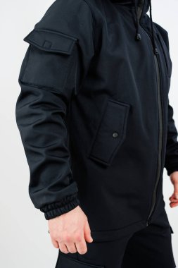 Bir adam şu anda siyah bir ceket giyiyor. Kapüşonu var. Kıyafetine bir tarz ve konfor katıyor.