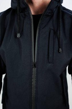 Bir adam şık siyah bir ceket giyiyor. Bu ceket, elementlere karşı sıcak ve korunaklı bir başlık içeriyor.