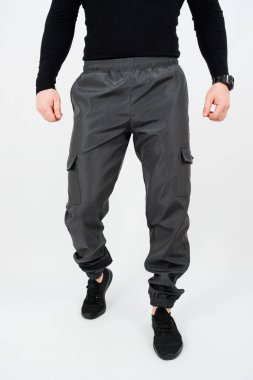 Bir adam şık bir siyah gömlek ve gri kargo pantolonu giyiyor. Hem işlevsel hem de modaya uygun. Çeşitli aktiviteler için mükemmel.