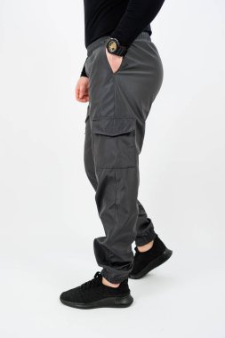 Şık siyah gömlekli ve rahat kargo pantolonlu bir adam elini cebine sokmuş.