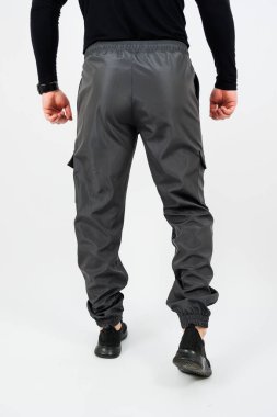 Siyah gömlekli, gri pantolonlu, sıradan ama şık bir kıyafet seçimi sergileyen bir adamın arka planı.