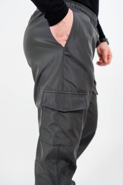 Kargo pantolonu giymiş bir adamın bir eli cebinde, rahat ve şık bir görünüm sergiliyor.