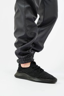 Aynı siyah ayakkabıyla şık siyah pantolon giyen biri şık bir görünüme sahip.