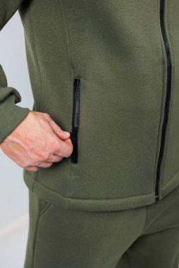 Bu parlak ve yenilikçi cep tasarımını ön plana çıkaran zeytin yeşili atletik bir ceketin yakın plan görüntüsü.