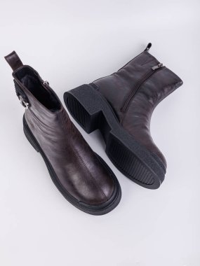 Beyaz arka planda hakiki deriden yapılmış düz tabanlı kadın botları. Sonbahar gündelik kadın ayakkabıları.