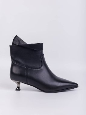 Zarif kadın çizmeleri. Siyah topuklu, hakiki deri ayakkabılar. Beyaz arka planda bağlayıcılar var. Her gün için şık sonbahar kadın ayakkabıları.