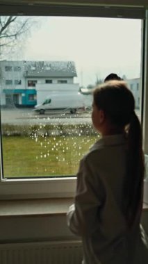 Genç bir kadın pencereyi özel bir kimyasal maddeyle temizliyor. Cam temizleyici ve mikrofiber kullanıyor..