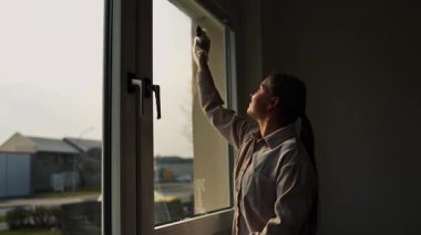 Cam silici. Oda servisi. Sabun solüsyonu pencereye sıçrar. Pencere temizleyicisi. Ev hanımı pencereyi temizler..