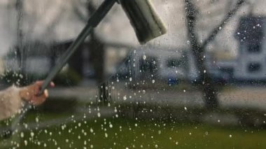 Cam silici. Oda servisi. Sabun solüsyonu pencereye sıçrar. Pencere temizleyicisi. Ev hanımı pencereyi temizler..