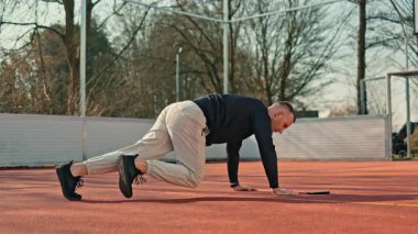 Bir adam açık hava spor sahasında spor yapıyor. Yazın vücut geliştirme egzersizleri yapan bir adam var..