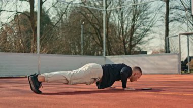 Bir adam açık hava spor sahasında spor yapıyor. Yazın vücut geliştirme egzersizleri yapan bir adam var..