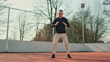 Bir adam açık hava spor sahasında spor yapıyor. Yazın vücut geliştirme egzersizleri yapan bir adam var..