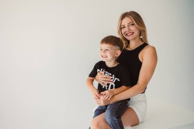 Neşeli ve neşeli bir anne, sevimli oğlunu şık, modern ve sanatsal bir stüdyoda kucaklıyor.