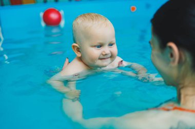 Anne ve bebek havuzda yüzmekten hoşlanırlar. Bebek bir cankurtaranla yüzmeyi öğreniyor..