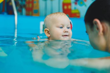 Anne ve bebek havuzda yüzmekten hoşlanırlar. Bebek bir cankurtaranla yüzmeyi öğreniyor..