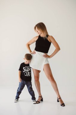 Parlak ve şık bir stüdyo ortamında, modaya uygun bir anne oğlunun yanında duruyor, modern tarzlarını ve paylaştıkları güçlü aile bağlarını sergiliyor.