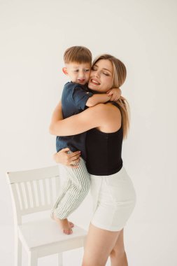 Neşeli bir ebeveyn çocuk etkileşimi parlak bir stüdyoda çekiliyor, neşeli bir kucaklaşma sırasında sevgilerini sergiliyorlar, aile temalı projeler için ideal.