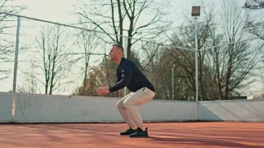 Bir adam açık hava spor sahasında spor yapıyor. Yazın vücut geliştirme egzersizleri yapan bir adam var..