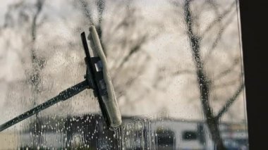 Kadın evin camını sprey ve paspasla elle yıkıyor. Yükseklikte güvenlik, bahar temizliği, temizlik hizmetleri