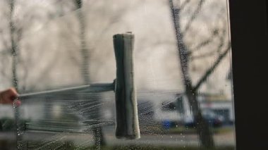 Kadın evin camını sprey ve paspasla elle yıkıyor. Yükseklikte güvenlik, bahar temizliği, temizlik hizmetleri