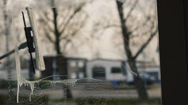 Kadın evin camını sprey ve paspasla elle yıkıyor. Yükseklikte güvenlik, bahar temizliği, temizlik hizmetleri