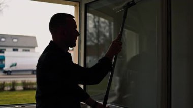 Genç adam camları temizliyor. Çok katlı bir binayı temizliyorum. Cam için özel kimyasallar