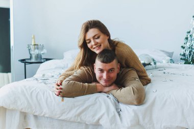 Neşeli bir çift, güzel dekore edilmiş bir yatak odasında, sevgilerini ve kutlamalarının ruhunu yansıtan samimi ve samimi bir anı paylaşıyor ve onunla eğleniyor.