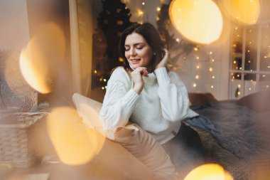 Yeni yıl mekanlarında hoş bir kız rahat bir oturma odasında. Yeni yıl için evdeki kadın.