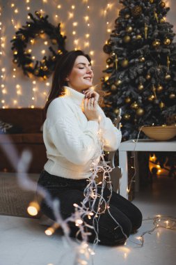 Yeni yıl mekanlarında hoş bir kız rahat bir oturma odasında. Yeni yıl için evdeki kadın.