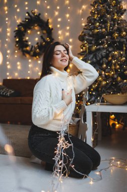 Yeni yıl mekanlarında hoş bir kız rahat bir oturma odasında. Yeni yıl için evdeki kadın.