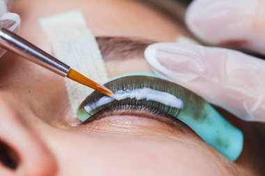 Yetenekli bir teknisyen hassas aletlerle güzel kirpik uzantıları uygular, sakin bir güzellik salonundaki karmaşık süreci gözler önüne serer, sanatın içeriğini vurgular.