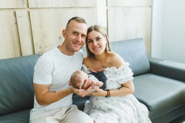 Yumuşak ışıkla dolu sıcak bir odada, neşeli bir çift yeni doğan bebeklerini kucaklar, sevgi ve umut dolu aile başlangıçlarını simgeleyen samimi bir anı yakalarlar.