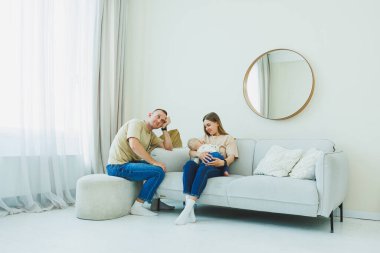 Sevgi dolu bir aile sahnesi, kendini bebeğine adamış ailelerin sıcak ışıklarla ve davetkar dokularla dolu sıcak bir oturma odasında bebeğini büyüttüğünü ve huzur ve sükunet yarattığını gösteriyor.