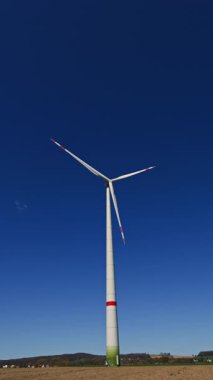 Mavi gökyüzü arka planında yel değirmenleri. Tarladaki güzel bulutlu gökyüzünde enerji üretimi için yel değirmeni çiftlikleri. Sürdürülebilir kalkınma için temiz yenilenebilir enerji üreten rüzgar türbinleri.