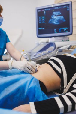 Hamilelik ultrasonu sırasında doktorun yanında yatan kadın. Hamilelik sırasında hamile kadını kontrol etmek.
