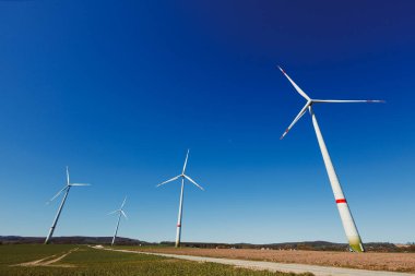 Rüzgar türbinleri açık mavi gökyüzüne karşı enerji üretiyor. Sürdürülebilir kalkınma için temiz yenilenebilir enerji üreten rüzgar türbinleri