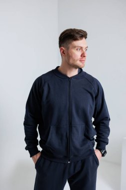 Koyu renk kapüşonlu bir kapüşonlu giyen şık bir genç modern ortamda rahat ve uysal bir hava yayıyor ve son moda ve yaşam tarzını vurguluyor.