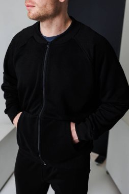 Kendine güvenen bir erkek model, gösterişli, siyah fermuarlı bir ceketle podyumda kasıla kasıla yürüyor. Moda ve şık bir parça, günlük geziler ve sosyal toplantılar için ideal.