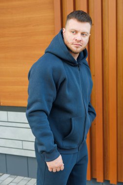 Moda bir donanma kapüşonlu kendine güvenen bir adam modern bir şehir görüntüsü sunar. Sıcak ahşap tonlarla çelişir. Forma ve moda için mükemmeldir.