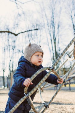 Çocuk dışarıda yürüyor. Çocuk bahçesinde yürüyüş yapan mutlu bir çocuk. Çocuk gelişimi, çocuğun sağlıklı yaşam tarzı. Çocuk sonbahar yürüyüşüne çıkmış. Şehir parkında neşeli bir çocuk.