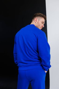 Canlı mavi eşofman giymiş şık bir adam, kendine güvenen bir moda anlayışını dinamik bir pozda sergiliyor. Bu da onu göz alıcı spor fotoğrafçılığı için mükemmel yapıyor.