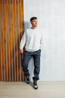 Şık bir genç adam, kendine güvenen rahat bir kıyafeti canlı bir ortamda sergiliyor. Benzersiz kişiliğini vurgulayan çelişkili dokular ve renkler sergiliyor.