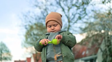 2 yaşındaki bir çocuk kumla oynuyor, kum havuzunda oturuyor. Çocuk oyun parkında oyun oynuyor. Henüz iki yaşında, temiz havada yürüyüşe çıkmış bir çocuk.