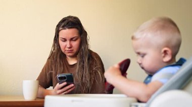 Anne blogcu, telefonu kendi başına yemek yiyen çocuğun yanına koyar. Annem telefona dikkat eder, çocuğa değil. Kadın, çocuğuyla birlikte evde otururken uzaktan çalışıyor.