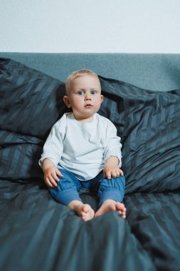 Pijama giyen, dinlenen ve yatakta oynayan 2 yaşında komik bir çocuk. Küçük çocuk yatakta oynuyor..