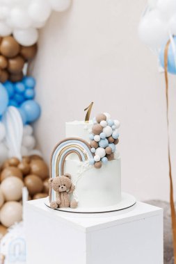 Doğum günü kutlaması için oyuncak ayıyla süslenmiş iki katlı tatlı pasta. Bir çocuğun ilk doğum günü için kek. Bir yaşındaki bir çocuk için Kek.