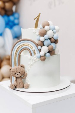 Doğum günü kutlaması için oyuncak ayıyla süslenmiş iki katlı tatlı pasta. Bir çocuğun ilk doğum günü için kek. Bir yaşındaki bir çocuk için Kek.