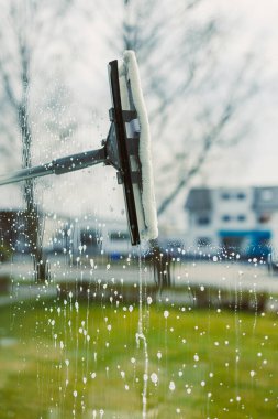 Profesyonel temizlik işçisi camları özel ekipmanlarla siler. Kadın pencereleri paspas ve cam temizleyicisiyle yıkıyor. Ev temizliği.