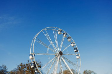 Mavi gökyüzüne karşı büyük bir dönme dolap. Dönme dolapta kamaralar.