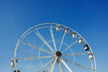 Mavi gökyüzüne karşı büyük bir dönme dolap. Dönme dolapta kamaralar.